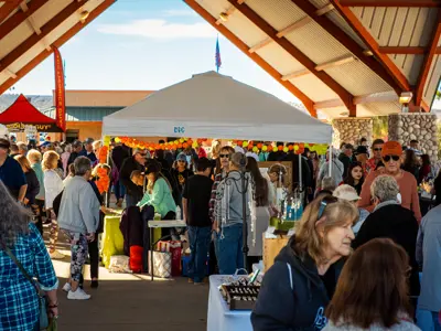 Crowd of people under the large ramada peruses vendors at Farmers Market
